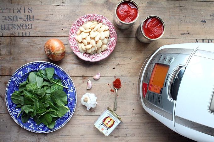 Spanish Beans and Tomatoes - flat lay of ingredients: tinned tomatoes, white beans, onion, spinach, garlic, smoked paprika